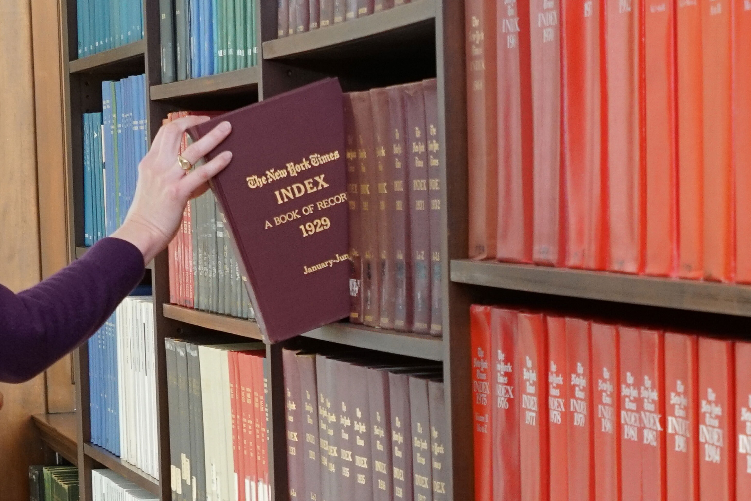 Periodicals Department - hand reaching for a bound volume of the New York Times Index